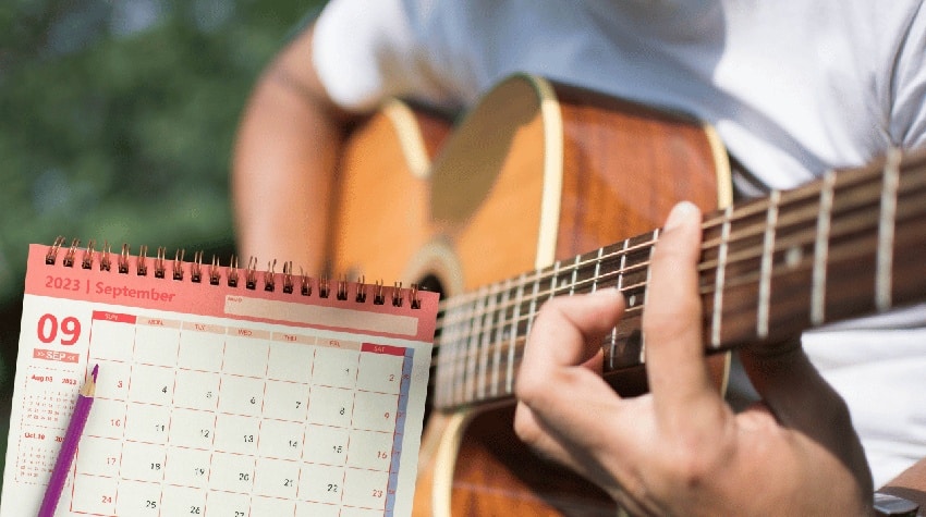 Un guitariste jouant de la guitare devant un calendrier, symbolisant l'importance de travailler régulièrement chaque jour pour éviter la stagnation et améliorer son niveau en guitare.